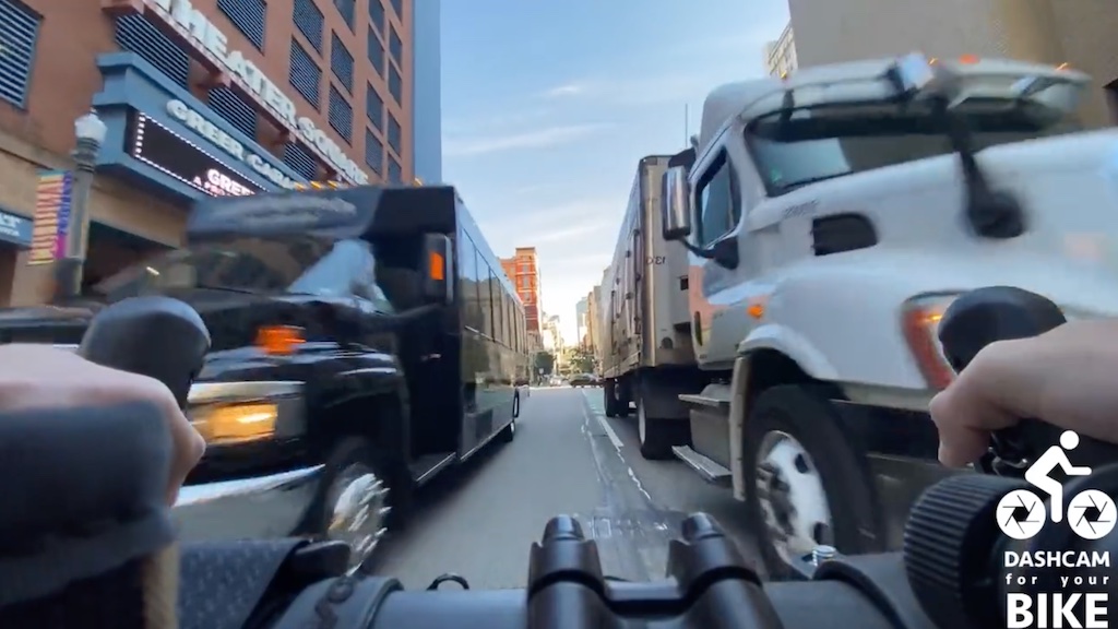 A bicyclist stuck between two trucks, caused by illegal parking in the bike lane